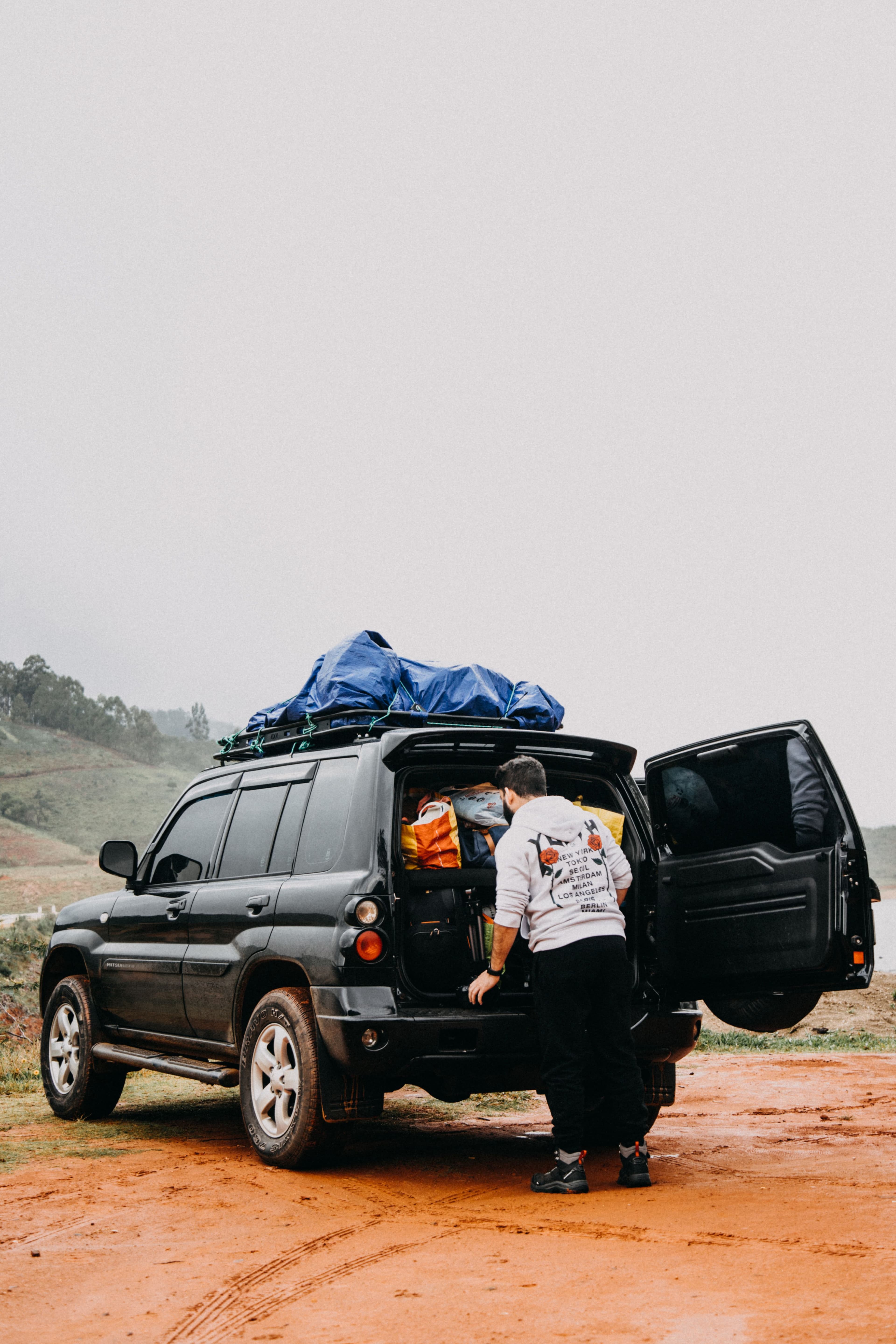A person loading camping gear into the back of a packed SUV