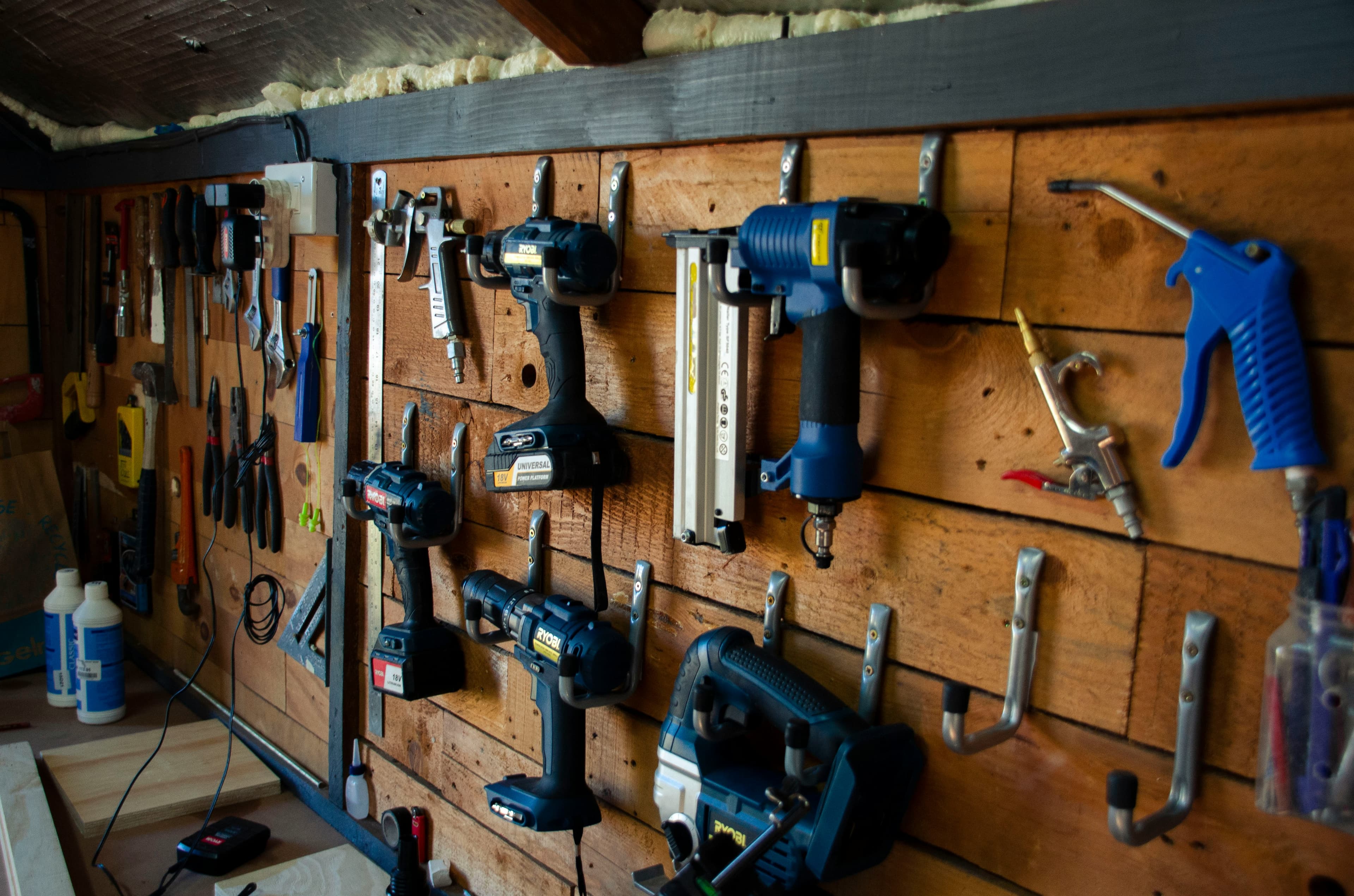 A workshop wall hung with cordless drills and power tools on hooks
